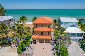 A multi-story building with a red-tiled roof, surrounded by palm trees and a beach view. - Bella Vista: Bay front with gorgeous views and outdoor living space. (Anna Maria)