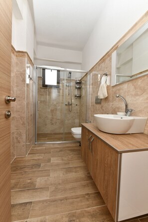 Familie appartement (B Blok) | Badkamer | Een douche, een regendouche, een haardroger, handdoeken
