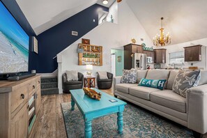 Un salon avec un téléviseur, un canapé, une table basse et un escalier.