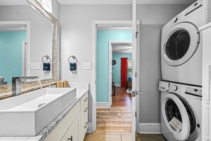 A modern bathroom with a large mirror, a sink, and a washing machine. - Family beach house w/ pool: 30A/Pier Park, Dog friendly, Golf Cart, West End PCB (Panama City Beach)