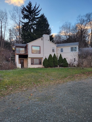 A two-story house with a stone facade, a large window, and a garage. - Rustic, Cozy Cottage with Backyard Waterfall and Cayuga Lake Views! (Ithaca)