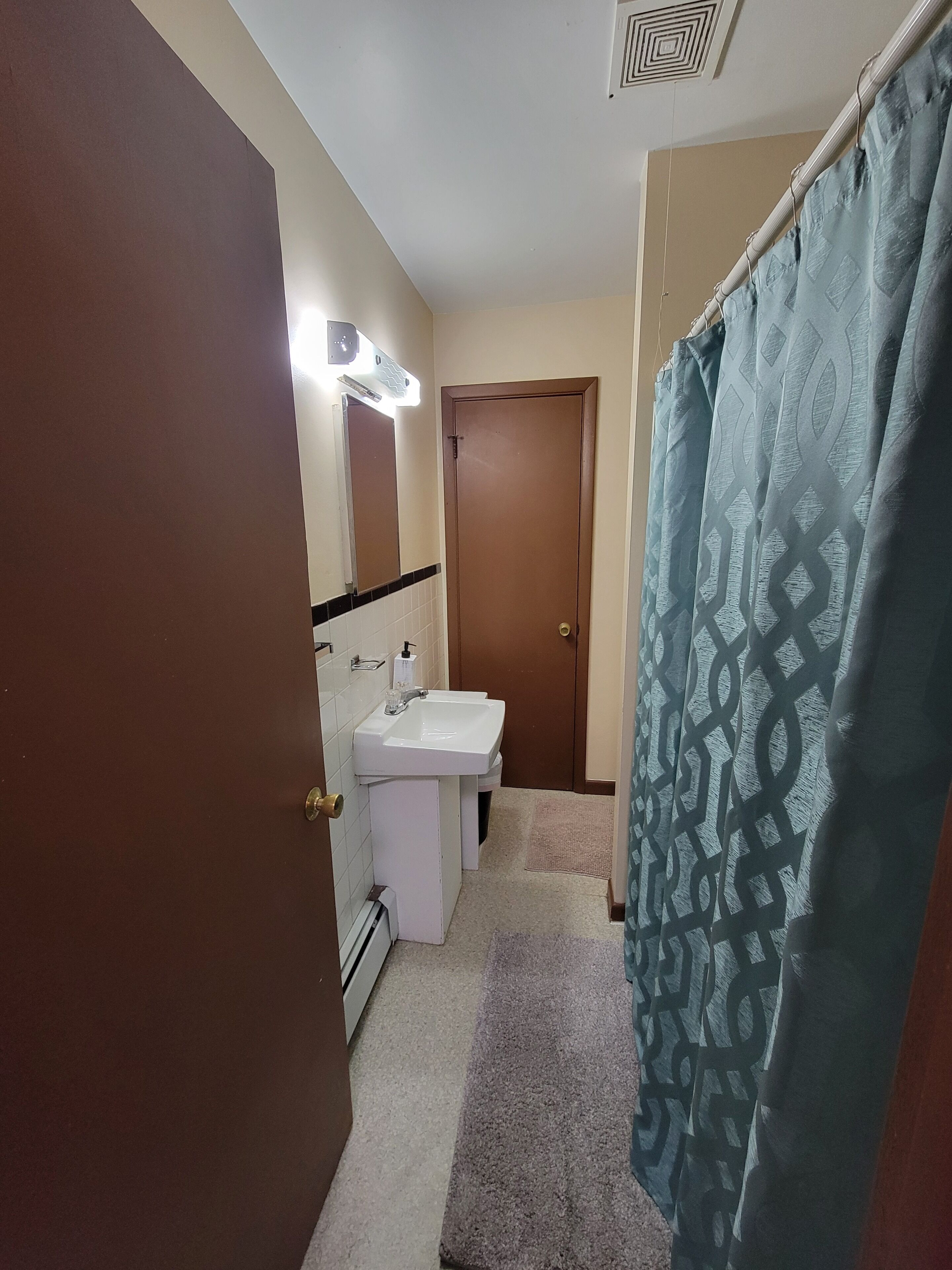 A bathroom with a white sink, a mirror, a towel rack, and a shower curtain.