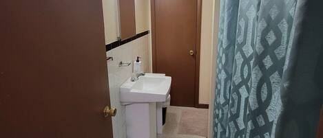 A bathroom with a white sink, a mirror, a towel rack, and a shower curtain.