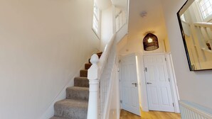 Eine Treppe mit Teppichstufen, weißen Geländern und einer weißen Tür am Fuß.