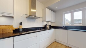 A modern kitchen with white cabinets, a black countertop, and a window providing a view of the outside.