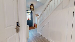 A hallway with a white door, a blue door, and a staircase with white railings.