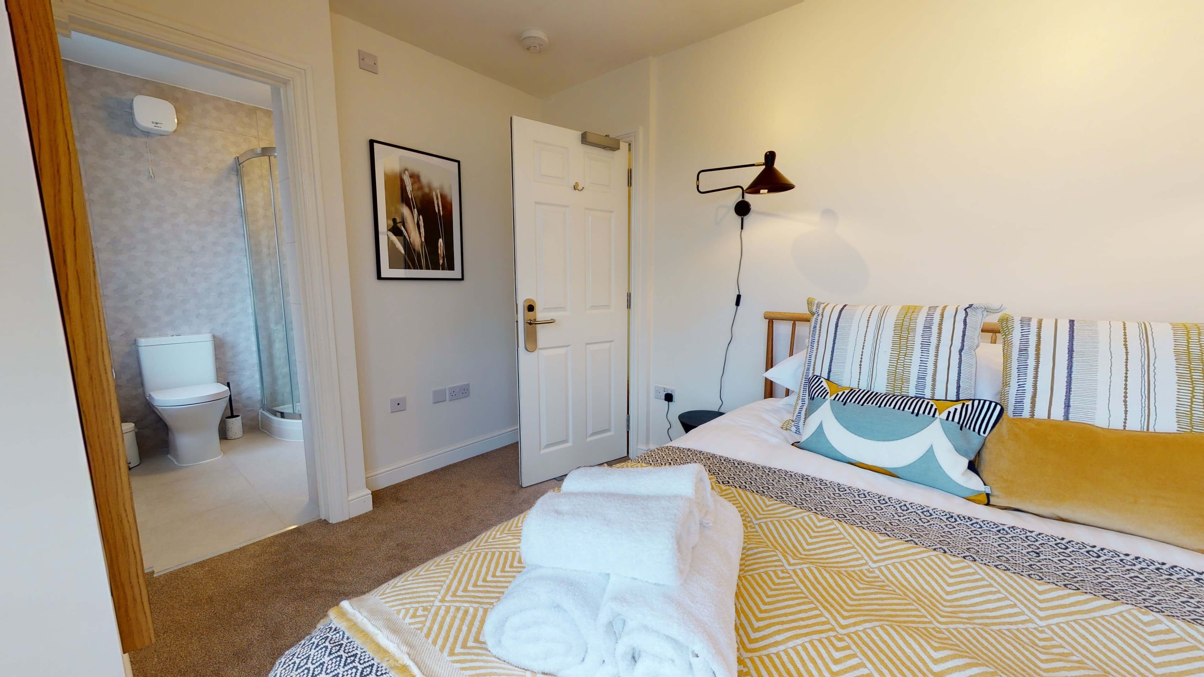 A hotel room with a bed, a bathroom, and a shower.