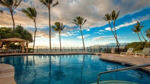 A swimming pool with lounge chairs and palm trees, surrounded by a fence and a view of the sky. - Fabulous Ocean Views, Steps From Polo Beach, Luxury 2 Bed 2 Bath (Kihei)