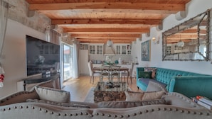 A spacious living area with a wooden ceiling, a large TV, a sofa, and a dining table with chairs. - Villa Vista (Petrovac)