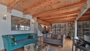 A spacious living room with wooden beams, a teal sofa, a grey sofa, a coffee table, and a bookshelf. - Villa Vista (Petrovac)