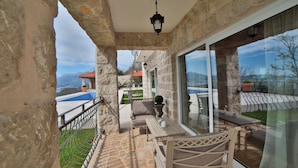 A balcony with stone walls, a table, chairs, and a view of the landscape. - Villa Vista (Petrovac)