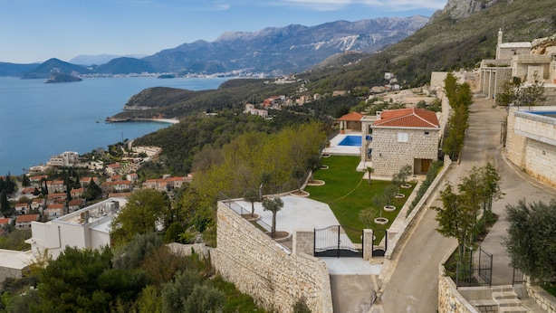 A coastal town with stone buildings, a clear view of the sea, and a mountainous backdrop. - Villa Vista (Petrovac)