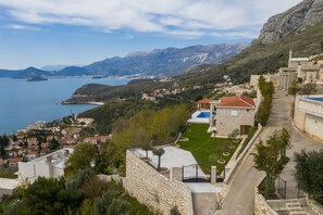 A coastal town with stone buildings, a clear view of the sea, and a mountainous backdrop. - Villa Vista (Petrovac)