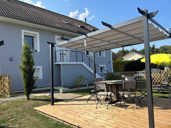 A modern house with a covered patio, outdoor furniture, and a small garden. - A Cozy 3*** Apartment in a House Near Annecy (La Balme-de-Sillingy)