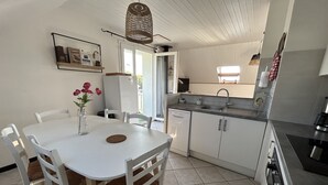 A modern kitchen with white cabinets, a dining table with chairs, and a hanging light fixture. - Le Cosy Home 3*** Apartment in house near Annecy (La Balme-de-Sillingy)