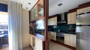 Eine moderne Küche mit Holzausstattung, einem Edelstahlkühlschrank, einer Mikrowelle und einem Herd.