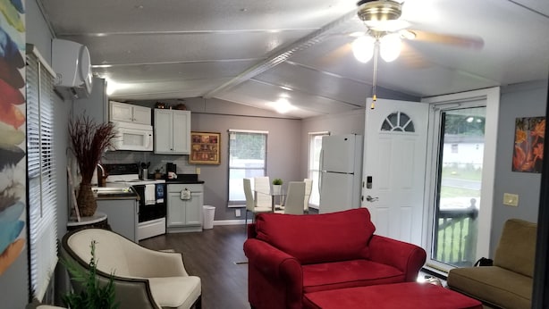 Un espacio habitable compacto con kitchenette, un sofá rojo y una zona de comedor.