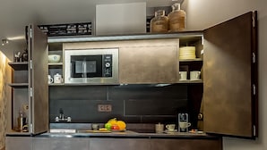 Una cucina moderna con mobili in legno scuro, forno a microonde integrato e cappa aspirante in acciaio inossidabile.