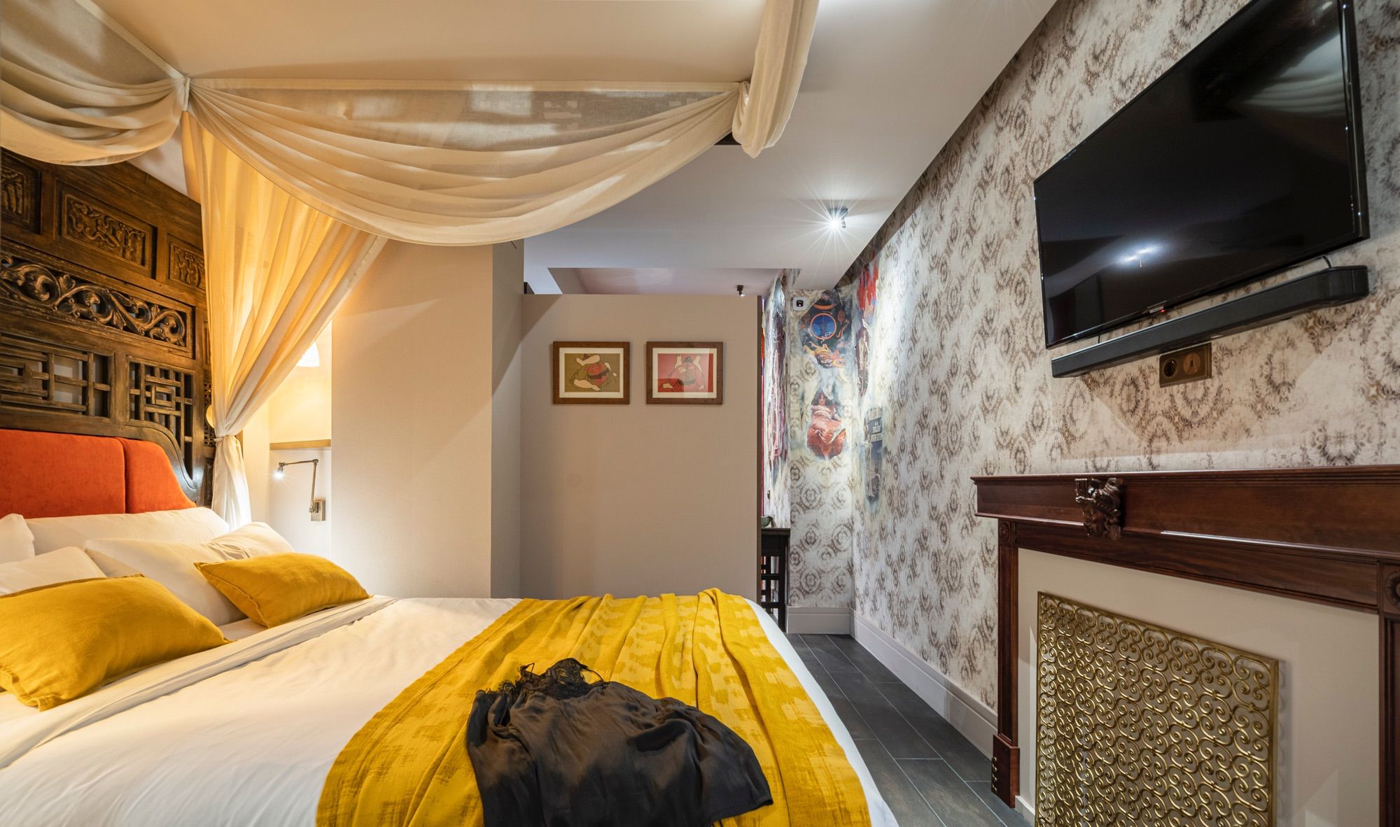 A hotel room with a bed, a television, a fireplace, and a patterned wall.