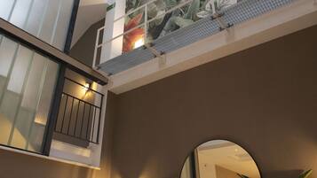 Ein mehrgeschossiges Interieur mit Balkon, einer großen Blumenwand, Korbsesseln und einem runden Spiegel.