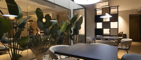 A modern meeting room with a glass partition, a large table, and comfortable chairs.