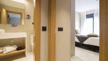 A modern bathroom with a wooden vanity, a mirror, and a toilet.