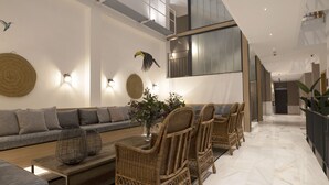 A modern interior with a sofa, wicker chairs, a coffee table, and decorative wall art. - Goodnight Cádiz Apartments (Cádiz)