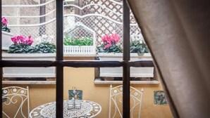 A courtyard with a round table and chairs, surrounded by a lattice fence and potted plants.