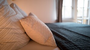 A bed with multiple pillows and a quilted blanket.