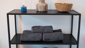 A black metal console table with three shelves, each holding folded grey blankets.