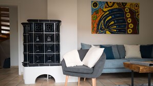 A living room with a black cabinet, a grey armchair, a blue sofa, and a colorful abstract painting on the wall.
