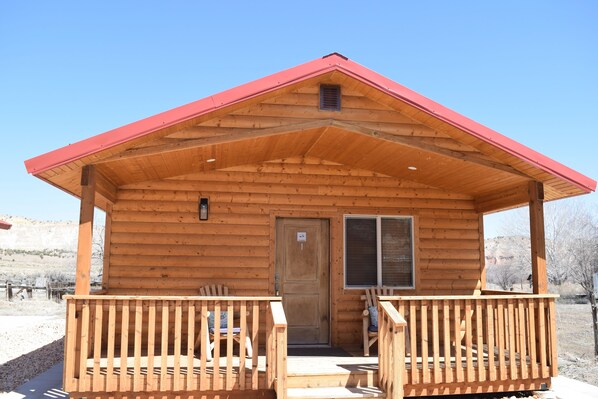 A wooden cabin with a red roof, a porch with two chairs, and a door. - Quaint and spacious cabin in the heart of Bryce Canyon Country  (Cannonville)