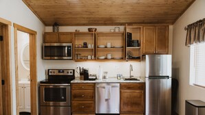 A modern kitchen with wooden cabinets, stainless steel appliances, and a wooden floor.
