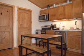 A kitchen with wooden cabinets, a microwave, a stove, and a sink. - Quaint and spacious cabin in the heart of Bryce Canyon Country  (Cannonville)