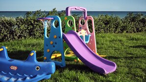 A playground with slides and climbing structures on a grassy field with a view of the sea. - Sea Side LaLune Villa, with Heated Pool & Spa Whirlpool (Zakynthos)