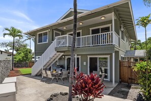 A two-story house with a balcony, outdoor seating area, and a staircase leading to the upper level.