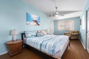 A bedroom with a bed, two nightstands, a ceiling fan, a window with blinds, and a door.