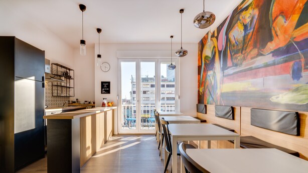 A modern kitchen with a central island, dining area with chairs, and a large window with a city view. - Bed and Breakfast Sky (Zagreb)