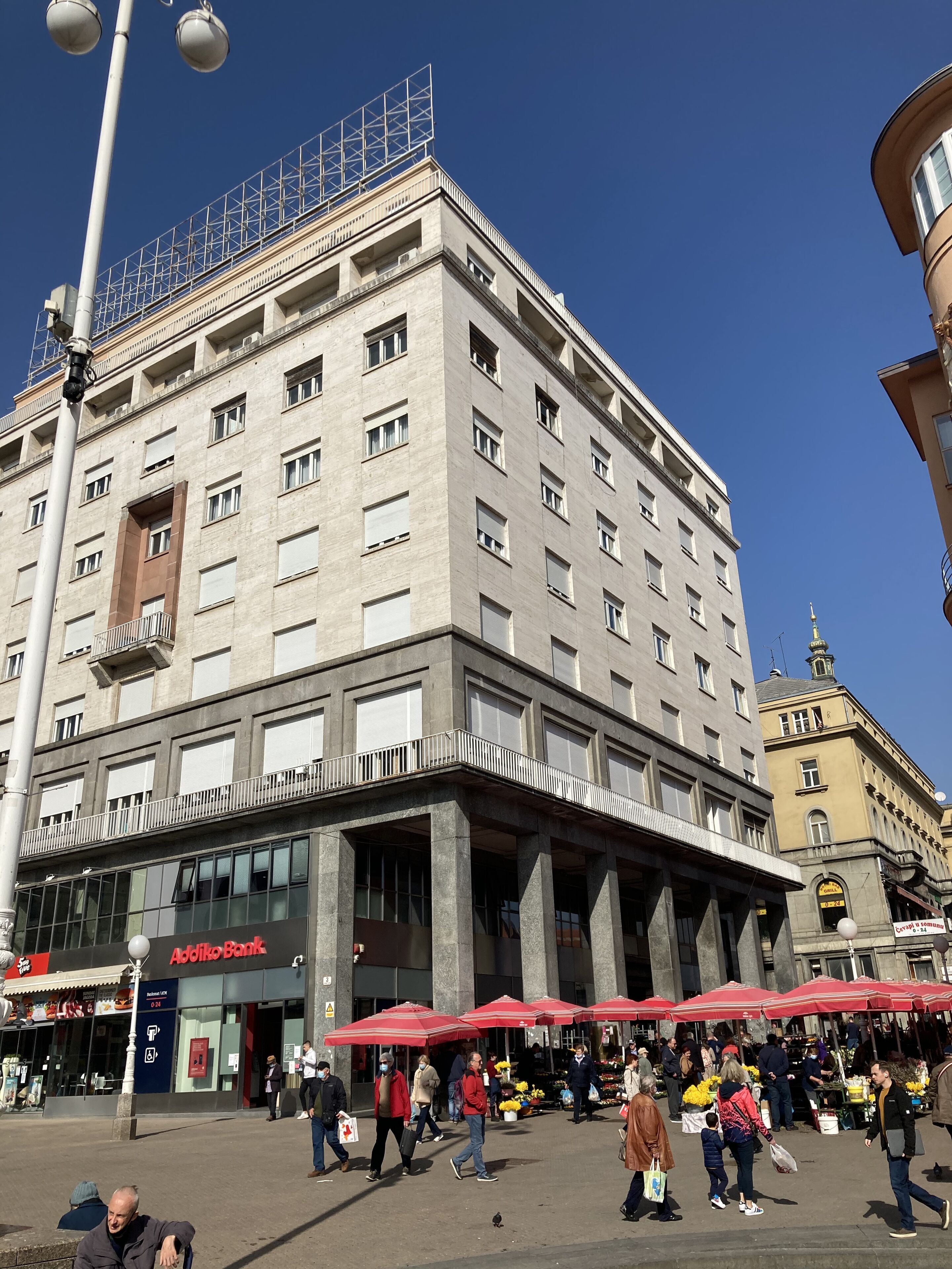 Um edifício moderno de vários andares, com design arquitetônico marcante, apresentando uma entrada destacada com fachada de vidro e um grande letreiro.
