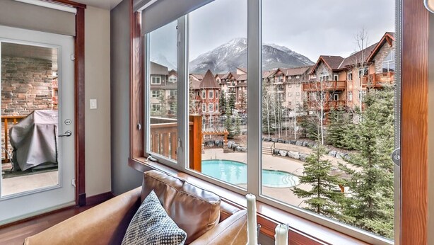 A room with a large window overlooking a pool and a mountain view.