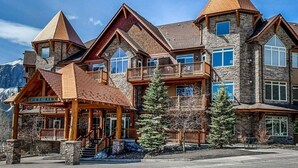A large, multi-story lodge with a stone facade, multiple balconies, and a prominent wooden entrance.