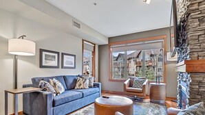 A modern living room with a blue sofa, a round coffee table, and a fireplace.