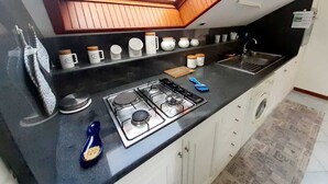 A kitchen with a gas stove, sink, and a skylight above the countertop.