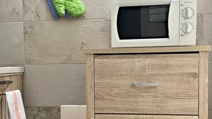 A bathroom with a wooden cabinet, a microwave on top, and a towel hanging on the wall. - Comodissimo Bilocale Dimora Raffaella (Torre Lapillo)