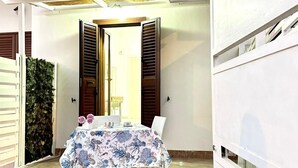A dining area with a table set for four, a white wall, and a wooden ceiling. - Comodissimo Bilocale Dimora Raffaella (Torre Lapillo)