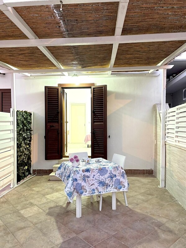 A small dining area with a table set for two, a wooden ceiling, and a door leading to another room. - Comodissimo Bilocale Dimora Raffaella (Torre Lapillo)