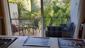 Een balkon met een tafel en stoelen, een bank en uitzicht op weelderige begroeiing.