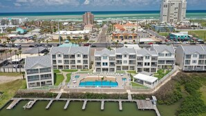 Un hotel costero con varias edificaciones, una piscina central y un puerto deportivo.