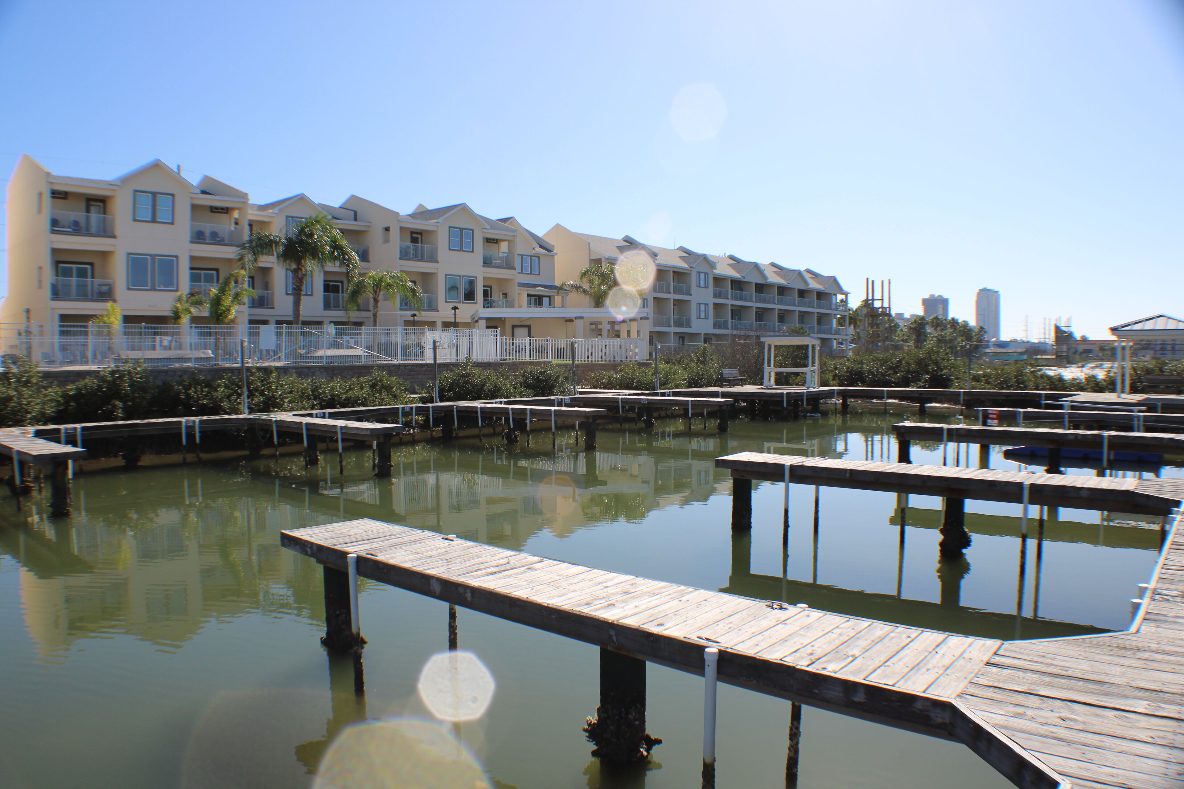 Un port de plaisance avec des quais en bois et un bâtiment doté de balcons en arrière-plan.