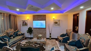 A luxurious living room with ornate furniture, a flat-screen TV, and decorative wall art. - The Festival Hotel Suites & Spa (Mtwapa)